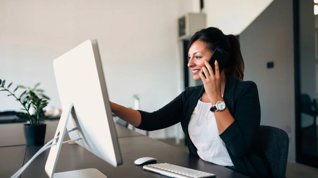 Une femme au téléphone devant un ordinateur