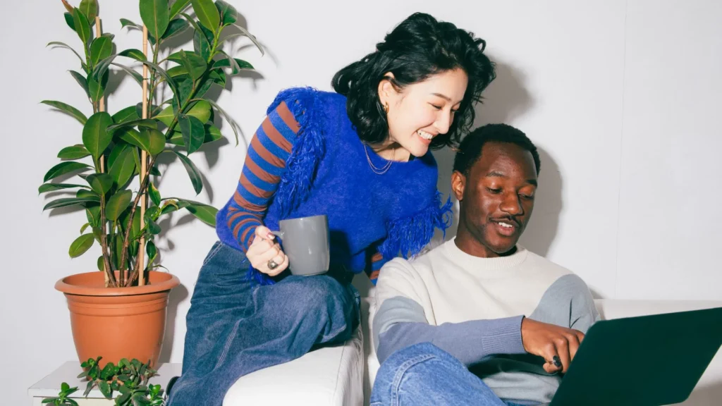 Un couple consulte un ordinateur portable, assis dans un canapé