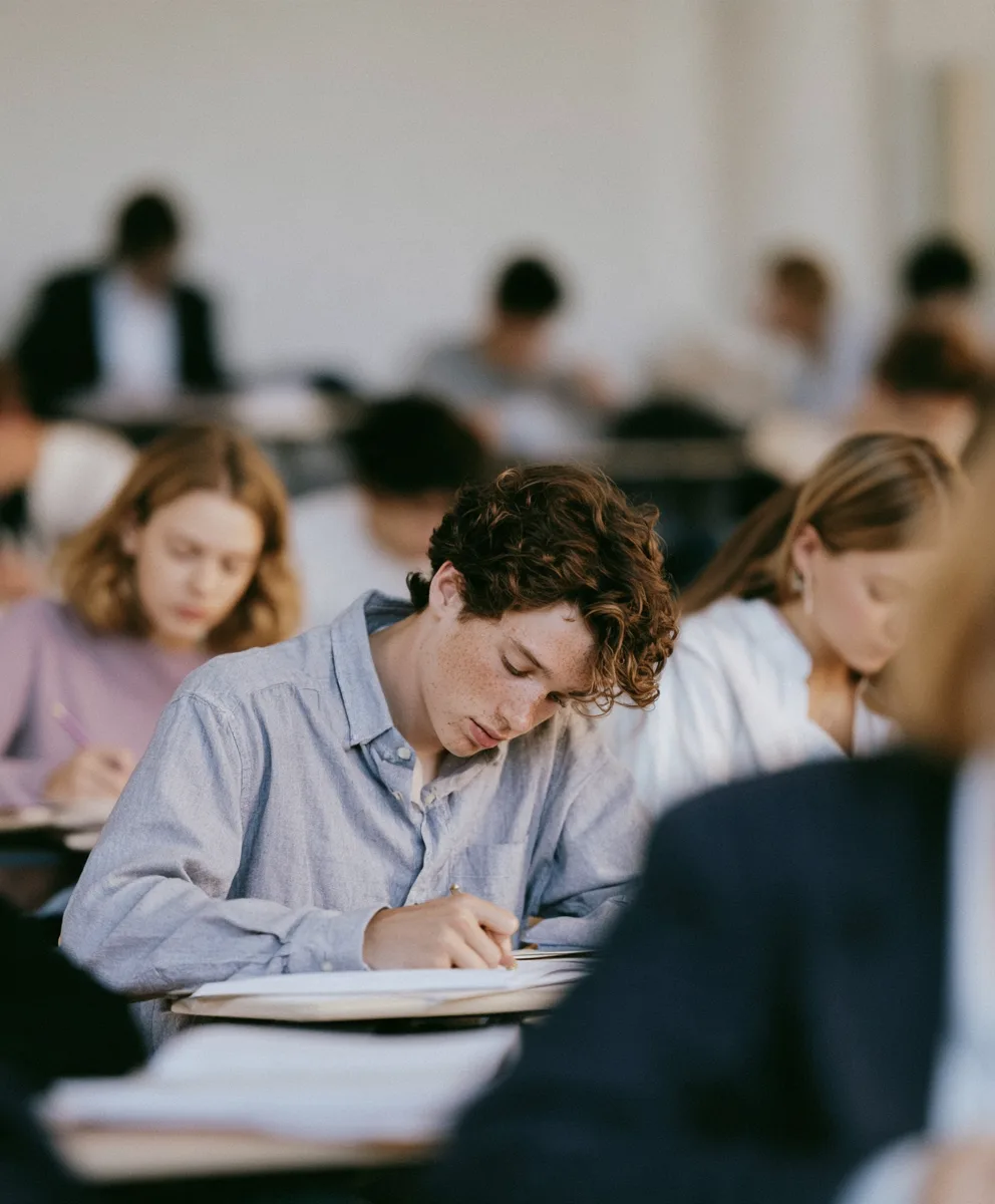 Des étudiants travaillent, penchés sur leurs copies, dans un amphithéâtre